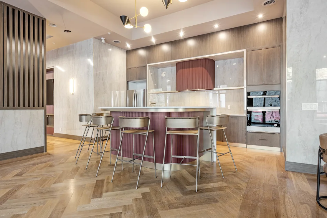 Clubhouse kitchen with a fluted burgundy island, brass stools and herringbone oak floors