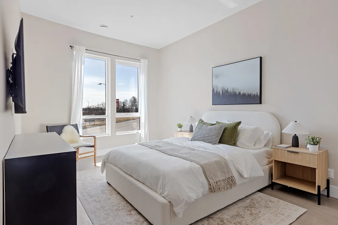 Bedroom with an upholstered bed and a wall-mounted television