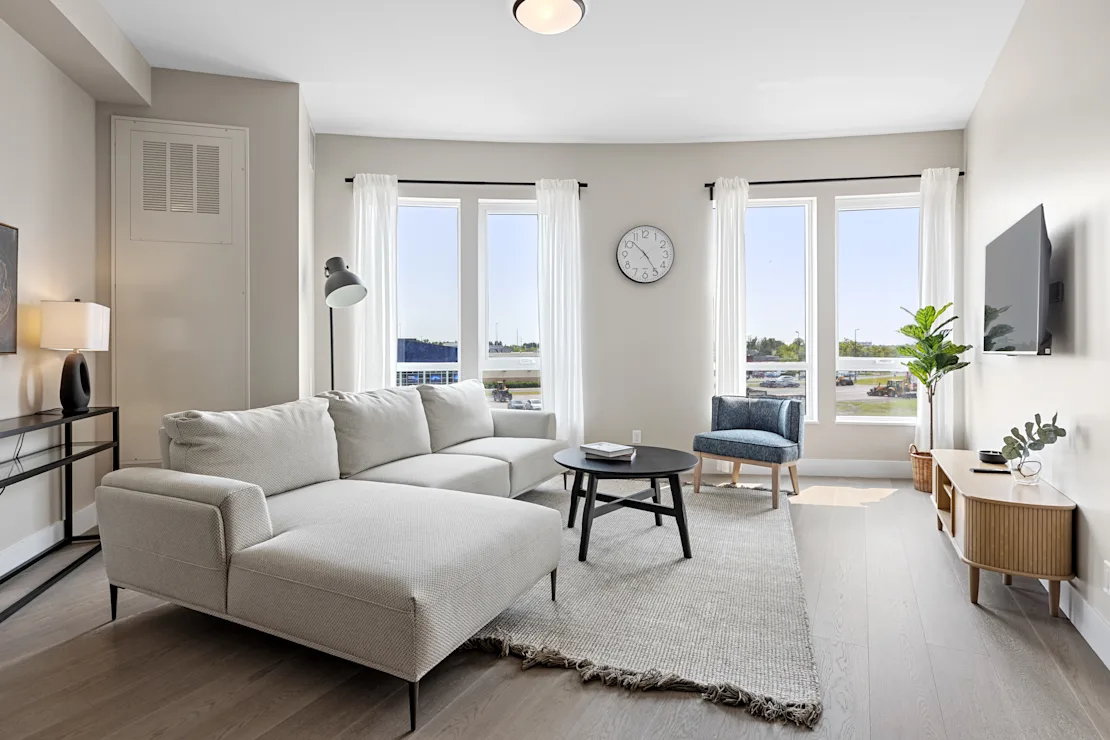 Living room with a pale sectional, black coffee table and corner windows