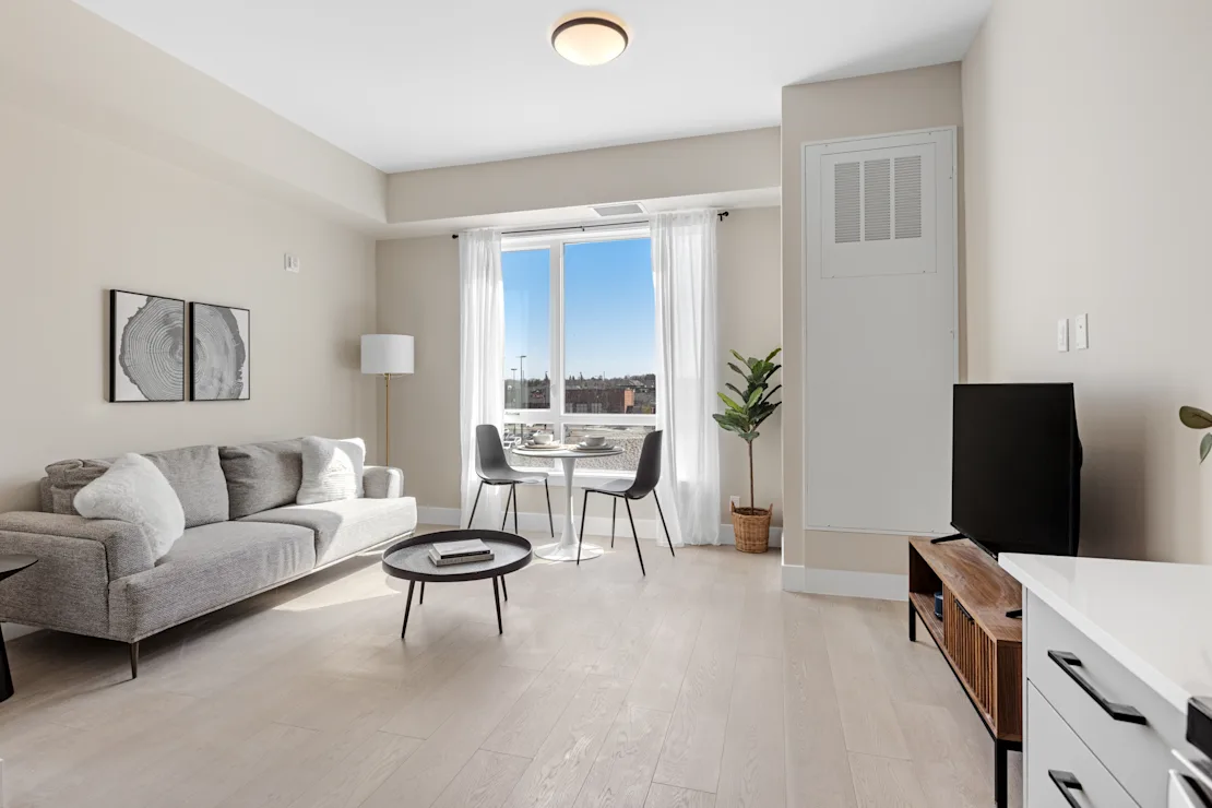 Living room with a grey couch and a wide city-facing window